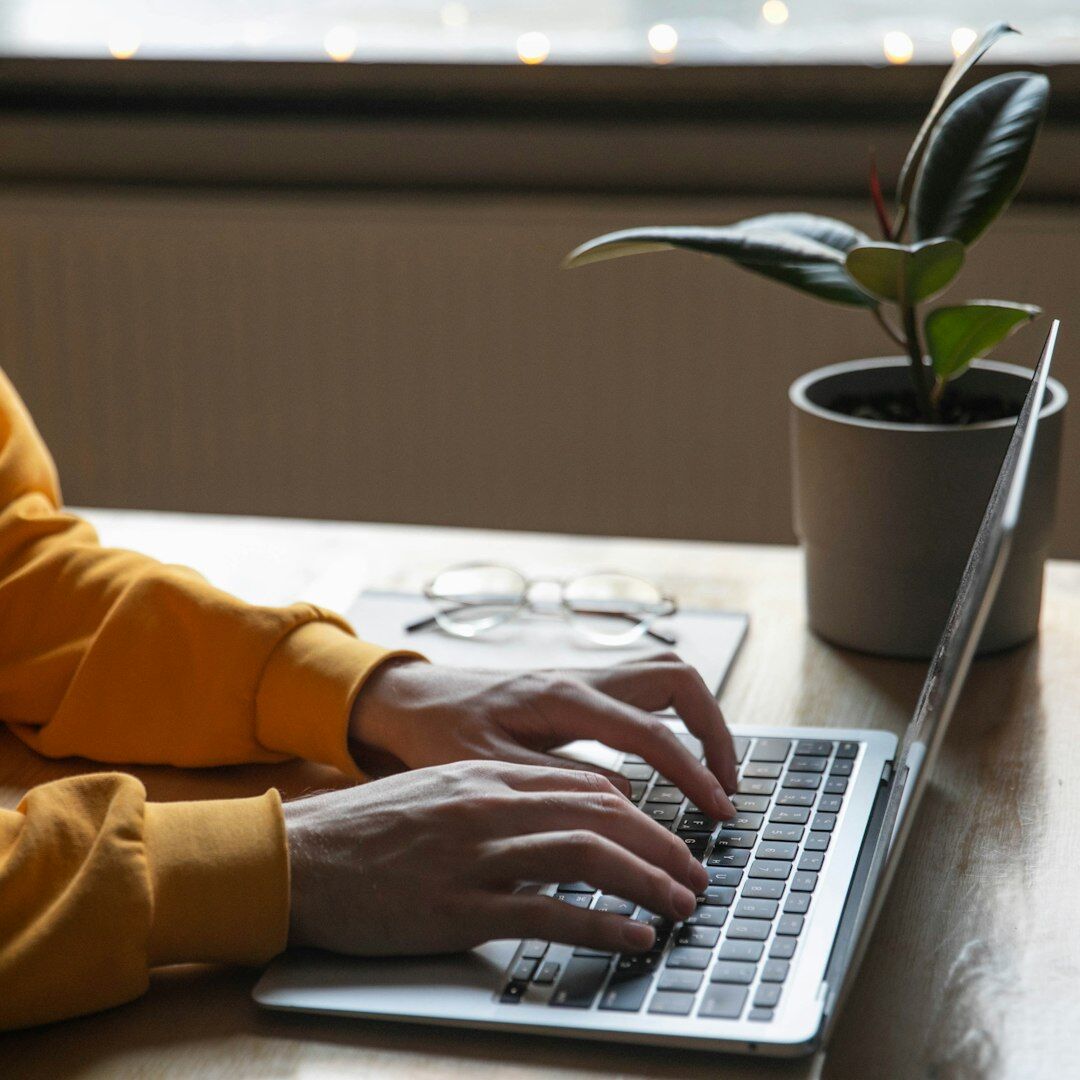 Portuguese woman writing notes next to a laptop at a desk
